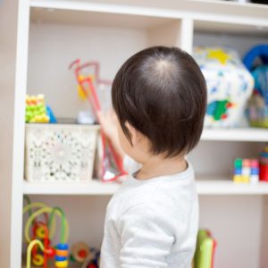 Toddler getting toys off a toy shelf