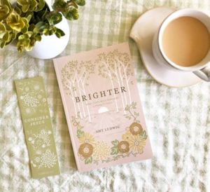 Picture of Brighter by Amy Ludwig by a bookmark, coffee, and plant