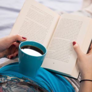 Finding time for yourself as a mom feature image of a woman holding a book and coffee.